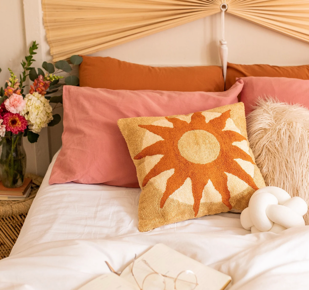 a bed topped with pillows and a decorative pillow